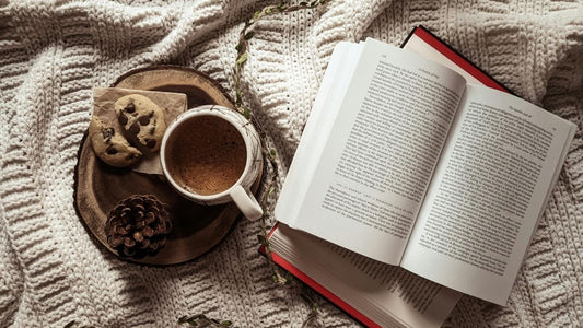 carte deschisă și o ceașcă de cafea pe o pătură, colț de citit confortabil pentru lectură zilnică