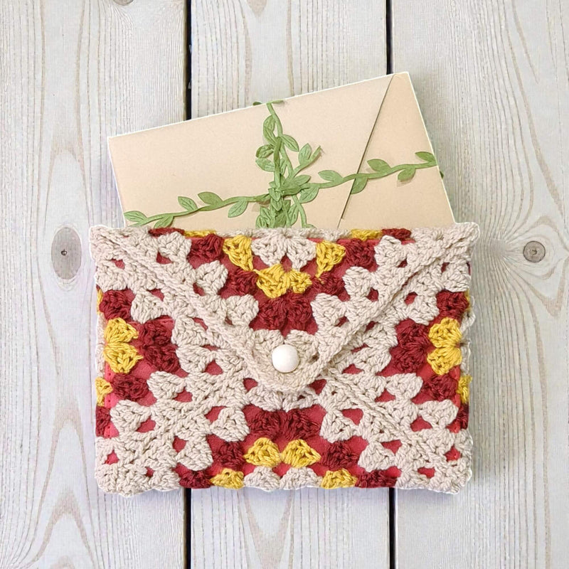 Husă de carte unicat croșetată cu model triunghiuri, în nuanțe crem, roșu burgund și galben, perfectă pentru cititori și colecționarii de accesorii pentru cărți în România.