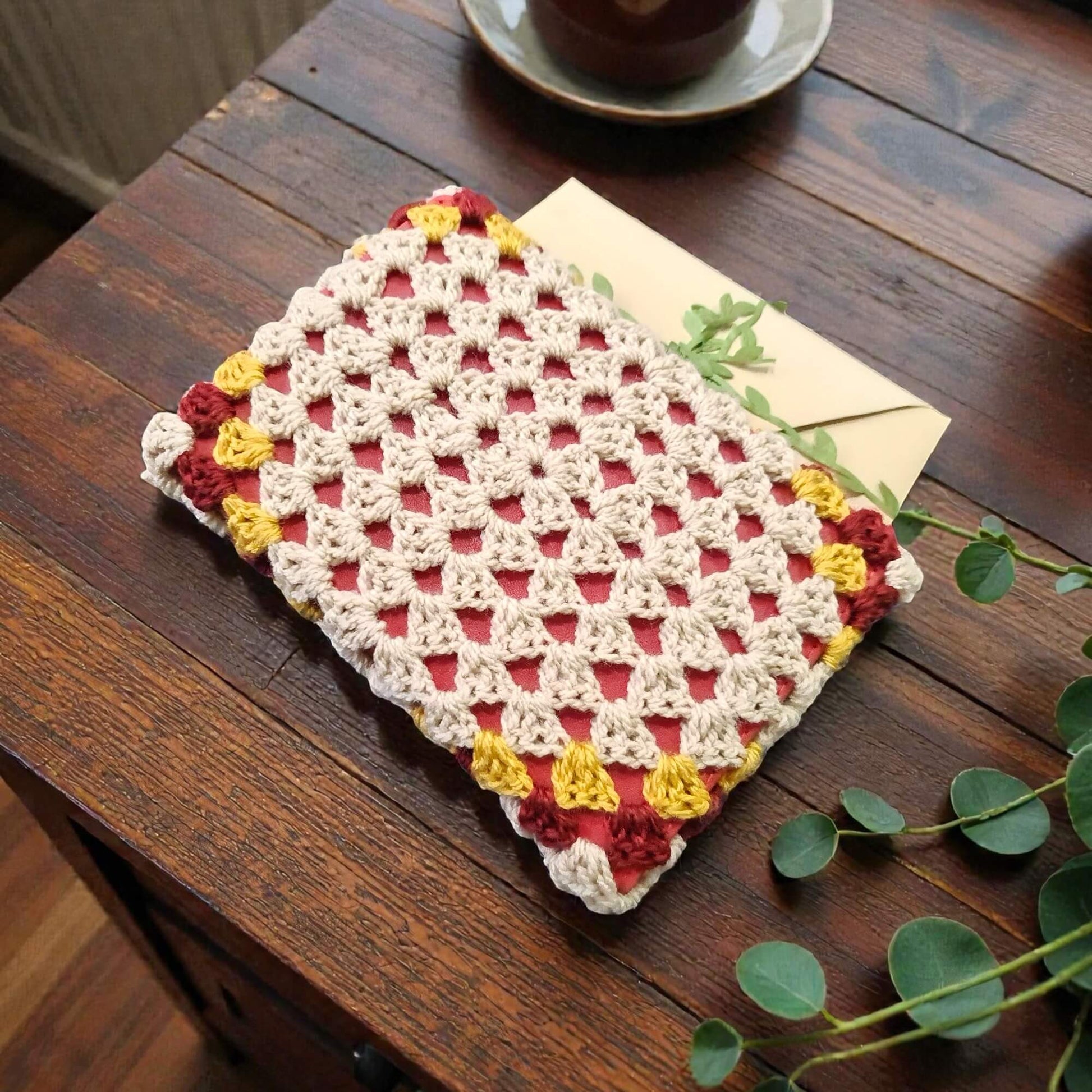 Husă de carte croșetată manual cu model triunghiuri, crem, roșu burgund și galben, unicat, perfectă pentru protejarea cărților și pasionații de lectură din România.