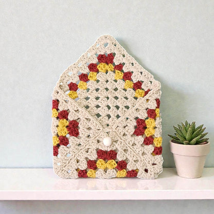 Husă de carte croșetată handmade cu model triunghiuri colorate crem, roșu burgund și galben, unicat, ideală pentru iubitorii de lectură și cadouri originale în România.