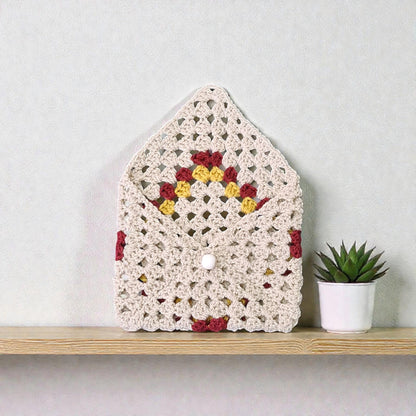 Husă croșetată manual, model romb colorat, oferă protecție delicată pentru carte, agendă sau tabletă mică.