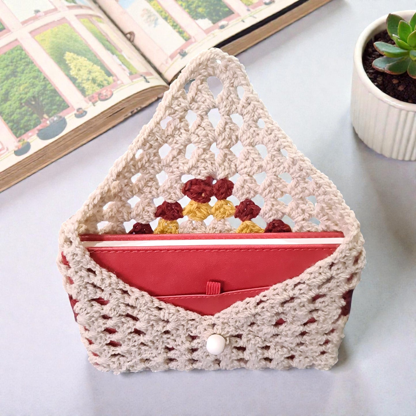 Piesă unică handmade, husă croșetată crem, burgund și galben, accesoriu stilat pentru lectură și organizare.