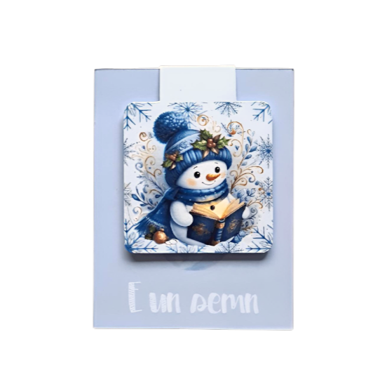 semn de carte magnetic cu ilustratie om de zapada care citeste in atmosfera de craciun