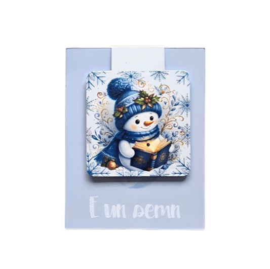 semn de carte magnetic cu ilustratie om de zapada care citeste in atmosfera de craciun